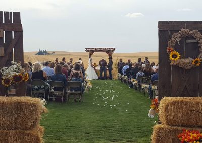 A bride and groom exchange vows in outdoor ceremony with rustic decorations